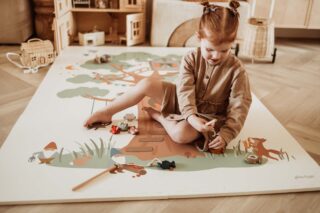 PlayandGo_EEVAA_treehouse_puzzlemat_child_sitting_on_the_mat_playing_with_wooden_toys